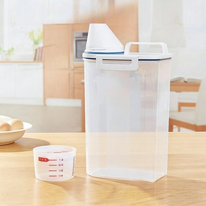 Clear plastic food storage container with airtight lid and measuring cup on wooden table