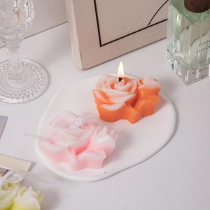 Rose shaped scented candle set on white ceramic tray with elegant home decor props