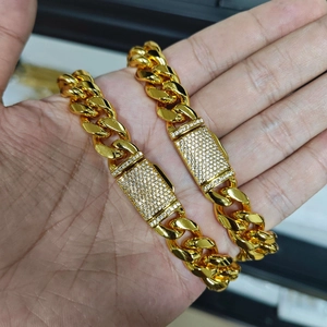Dettaglio di bracciali a catena cubana placcati oro con fibbie quadrate e zirconi