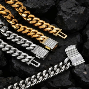 Dettaglio di catene cubane oro e argento con zirconi incastonati su roccia vulcanica nera