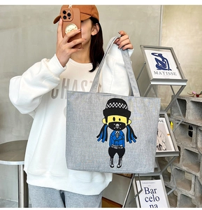Detail shot of grey canvas tote bag with trendy cartoon print and sturdy shoulder strap