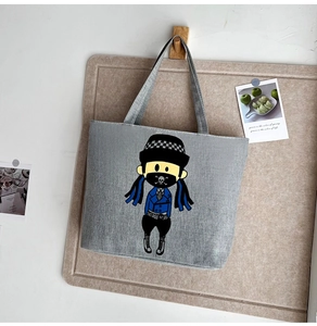 Detail of grey printed canvas tote bag hanging on a wooden hook with artistic vibes