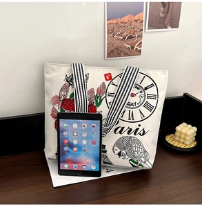 Close-up of large canvas tote bag with retro Paris print and striped handles for iPad storage