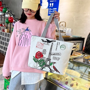 Casual white canvas tote bag with Eiffel Tower print and striped handles shown with model