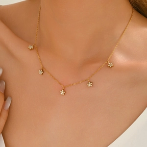 Elegant gold necklace with five zircon flower pendants worn on model's neck