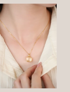 Close-up of a delicate gold S925 silver necklace with a square yellow crystal pendant
