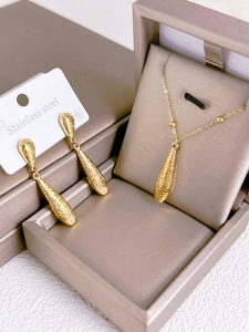 Macro shot of textured golden stainless steel water drop jewelry set with necklace and earrings