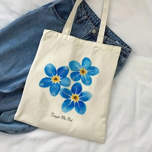 Detailed shot of canvas tote bag with blue forget-me-not print and lettering