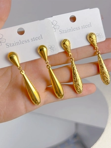 Detailed close-up of shiny polished and hammered gold teardrop earrings in stainless steel