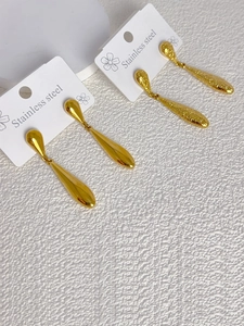 Detailed view of gold stainless steel teardrop earrings in polished and hammered finishes