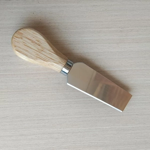 Detail of stainless steel cheese shovel with ergonomic wooden handle on wooden table