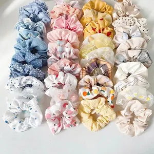 Detail of diverse hair scrunchies featuring floral, heart, and fruit patterns in multi-pack