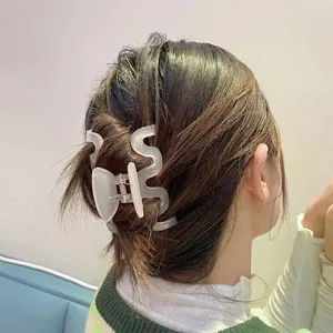 Matte translucent white large wave hair claw clip worn on model with dark hair