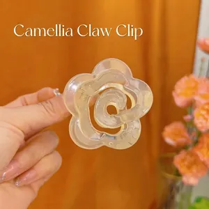 Close-up of a cream camellia flower hair claw clip made of translucent resin material