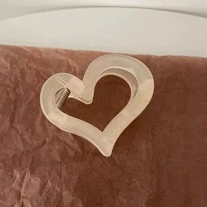 Close-up of minimalist heart-shaped hair claw clip with beige matte resin finish