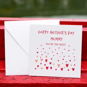 Minimalist Mother's Day greeting card with red hearts and envelope on wood background