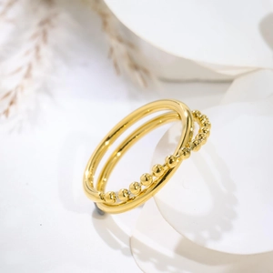 Macro detail of gold double-layered stackable ring with smooth band and bead chain texture