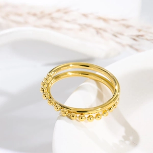 Elegant gold double-layered titanium steel ring with beads on a minimalist white backdrop