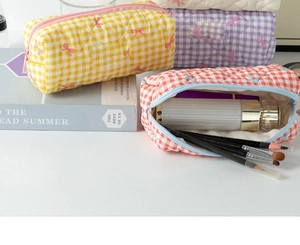 Detailed close-up of quilted cosmetic bags with bow prints and metal zipper closure