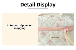 Close-up of smooth zipper closure on quilted makeup bag with pink bow pattern detail
