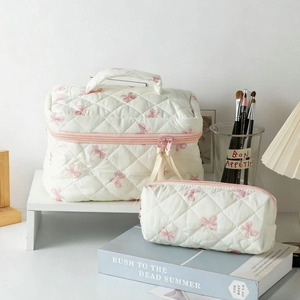 Quilted makeup bag set with pink bow pattern including large pouch and small clutch