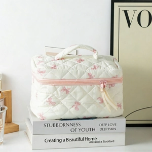 Quilted floral makeup bag with pink bow pattern and handle for portable cosmetic storage