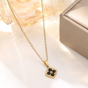 Macro detail of 18K gold-plated clover pendant with vintage brushed metal texture