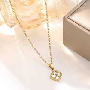 Detailed macro of vintage 18K gold-plated clover necklace with white petal inlay