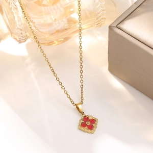 Macro shot of 18K gold plated vintage necklace with red clover leaf pendant in a jewelry box