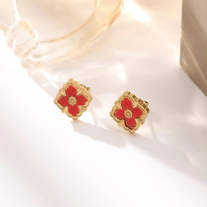 Macro shot of 18K gold leaf earrings with red clover motif and starburst texture
