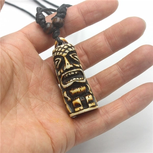 Macro detail of hand-carved resin Tiki totem pendant with adjustable black cord and beads