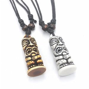 Close-up of brown and white Tiki pendants with tribal carvings and wooden beads