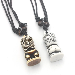 Detailed view of hand-carved Tiki totem pendants in brown and ivory with wooden beads