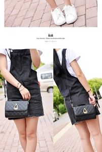 Detail of black quilted shoulder bag with gold teardrop-shaped rotary lock buckle