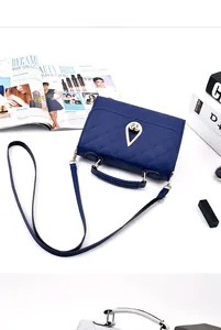 Detail of dark blue quilted handbag with gold teardrop clasp and leather handle