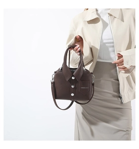 Close-up of a brown shirt-shaped crossbody bag with decorative buttons and strap on model