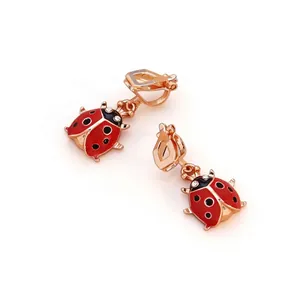Détail de boucles d'oreilles clips coccinelle en émail rouge et placage en or rose