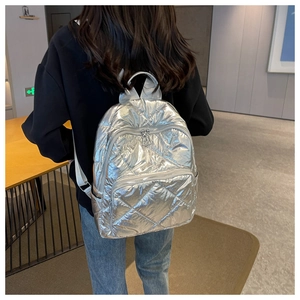 Detail des silbernen Metallic-Rucksacks mit gestepptem Muster und doppelten Reißverschlüssen