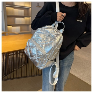 Detail eines silbernen Stepprucksacks mit Metallic-Struktur und weißen Trägern