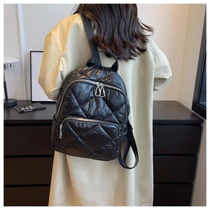 Moderner schwarzer Stepprucksack mit Rautenmuster, getragen von einem Model im Innenraum