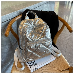 Nahaufnahme eines silbernen gesteppten Rucksacks mit Metallic-Finish auf einem Stuhl