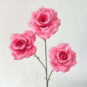 Close-up of artificial three-headed pink rose with gradient petals and green stem