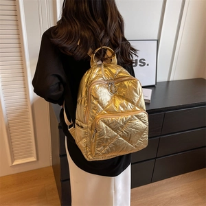Metallisch goldener Stepprucksack mit Rautenmuster, getragen von einem Modell