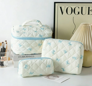 Three-piece quilted cotton makeup bag set with blue bow prints and top handle detail