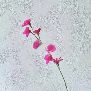 Detailed view of vibrant pink faux sweet pea flowers with realistic texture and green stems