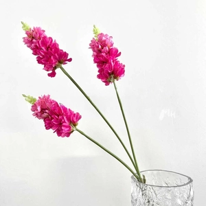 Three long-stemmed rose pink artificial flowers in a textured clear glass vase decoration