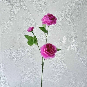 Detailed close-up of rose red artificial peony with lifelike petals and green leaves