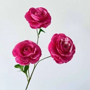 Close-up of three vibrant rose pink artificial peony flowers with green leaves