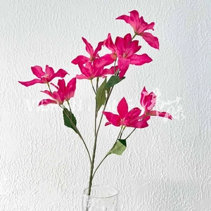 Detail of fuchsia silk artificial lily branch in glass vase for wedding decor
