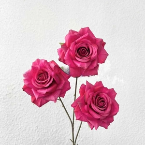 Macro detail of three vibrant magenta artificial silk roses for wedding floral decoration